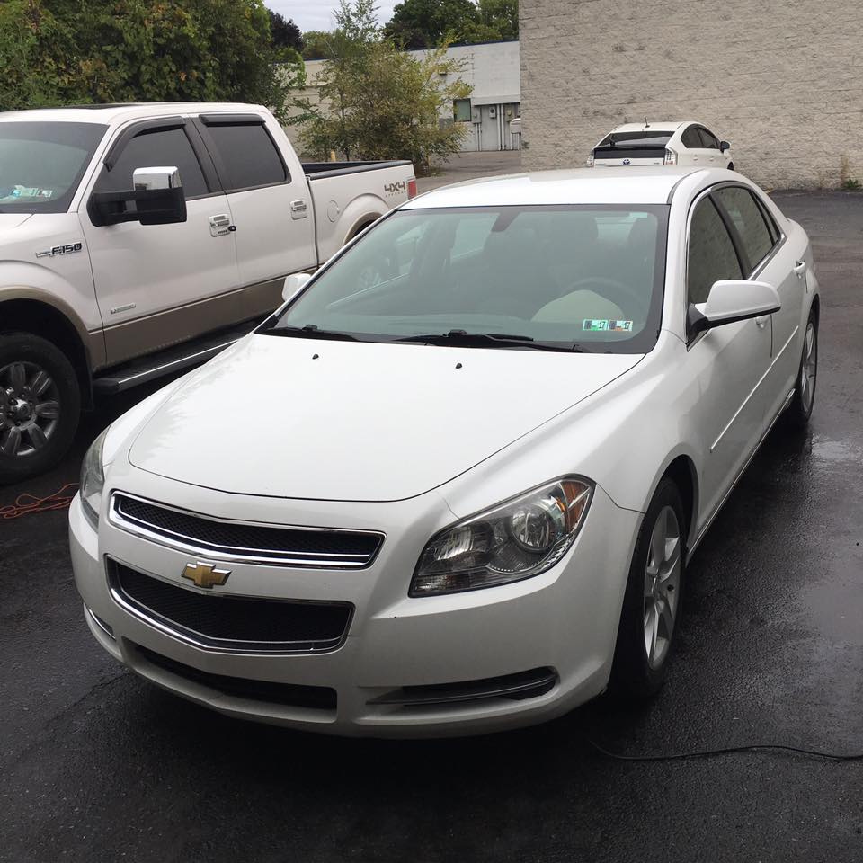 White Chevrolet sedan outside Ultimate Detailing